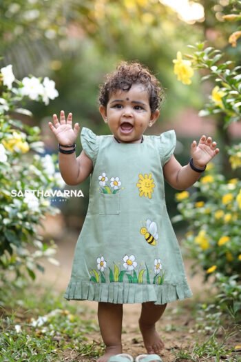 Baby girl wearing pastel green handpainted kids wear dress with floral and bee artwork